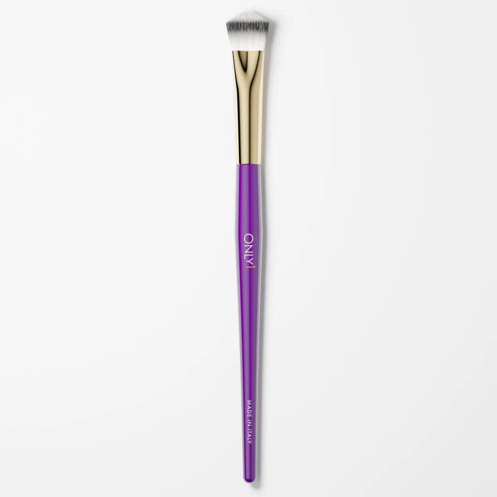Small concealing brush with a purple handle, gold accents, and white bristles on a plain white background.