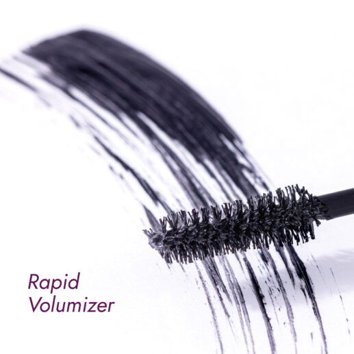 Mascara brush with volumizing mascara strokes on a white surface.