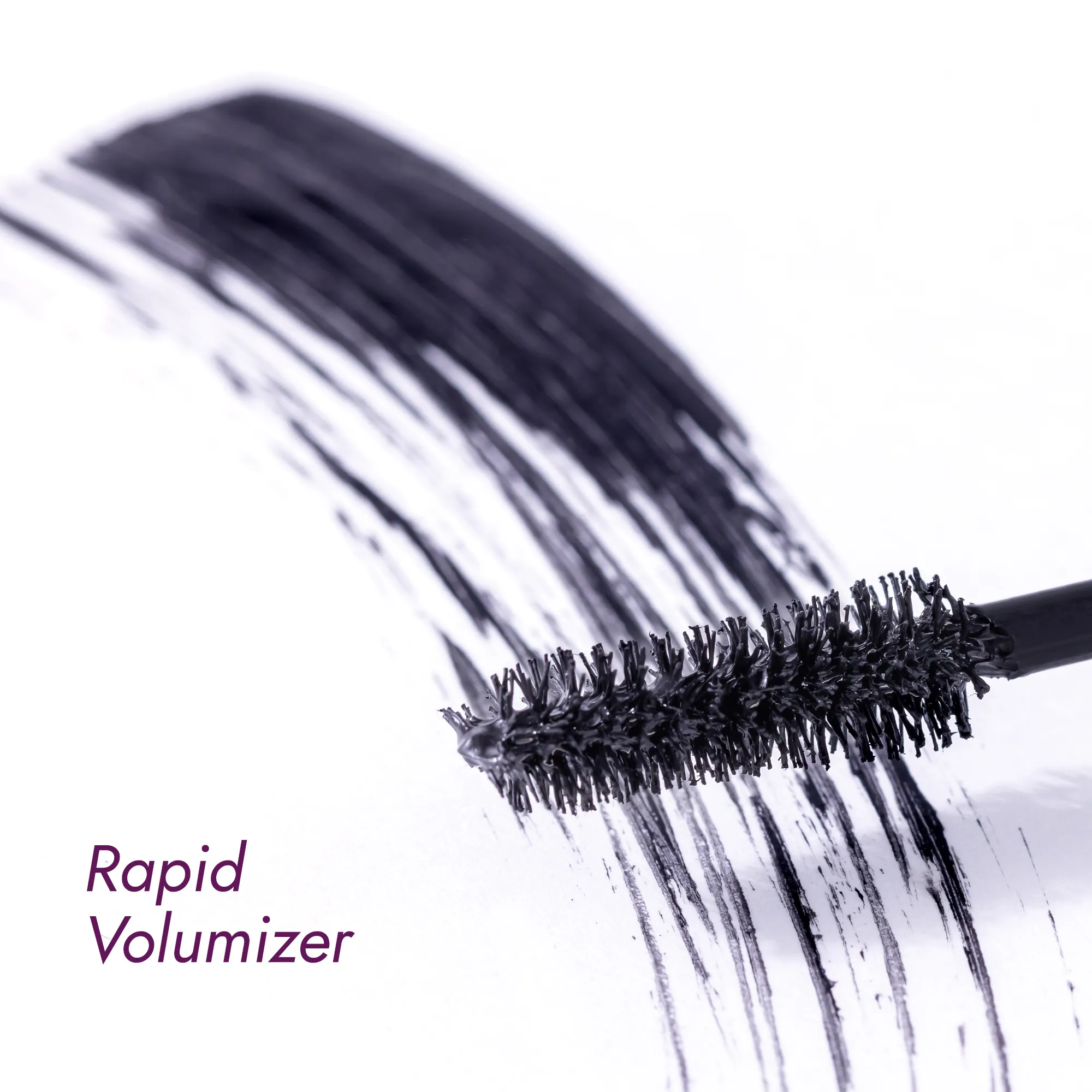 Mascara brush with volumizing mascara strokes on a white surface.