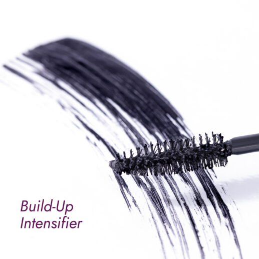 Mascara brush with volumizing mascara strokes on a white surface.