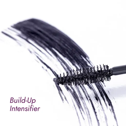 Mascara brush with volumizing mascara strokes on a white surface.