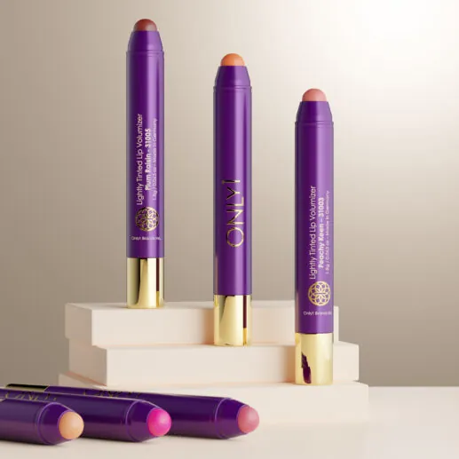 Lightly Tinted Lip Volumizer collection in purple and gold packaging, displayed with various shades