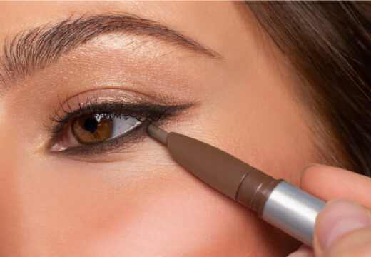 Close-up of a person applying eyeliner with brown eyes