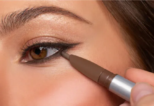 Close-up of a person applying eyeliner with brown eyes